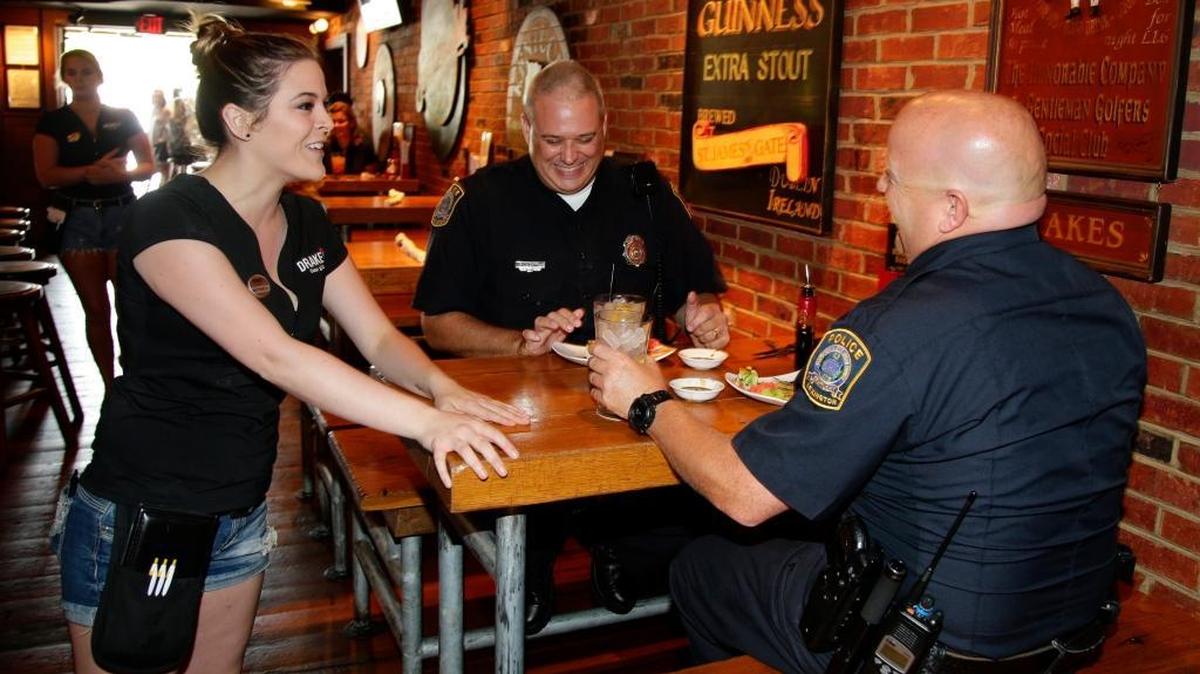 Drake’s server Michaela Pierceall chatted with officers Andy Cain, center, and Tim Ball, as Lexington Ky. police received meals on the house at Drake’s restaurants across the state on Monday July 18, 2016. Bluegrass Hospitality Group has announced a Drake’s will open in Nicholasville in 2018.