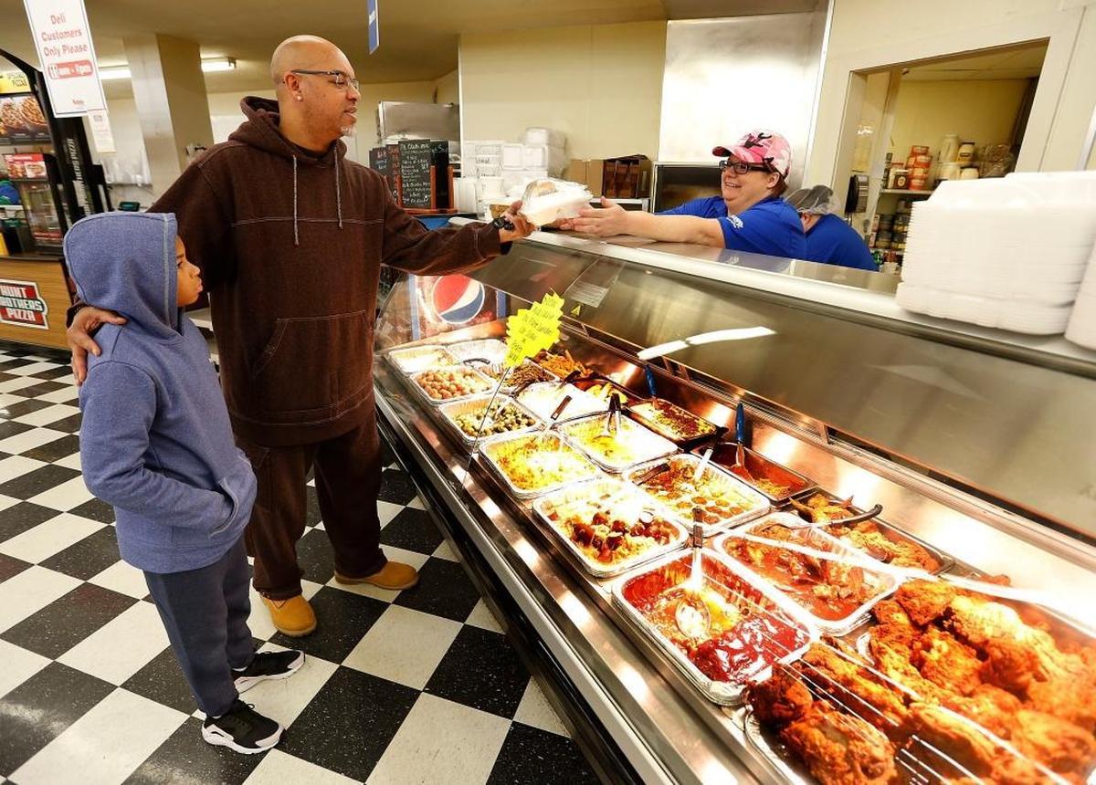 Regular customer Robi Berry, with his nephew Kenlon Johnson, received a fried chicken plate lunch from employee Meagan Elam during Tuesday lunchtime at Save-A-Lot, 398 Southland Drive in Lexington.