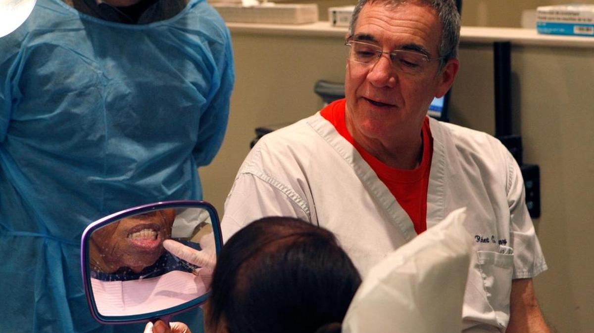 Dr. Robert Henry discusses a prosthetic denture with his client at the Mission Lexington Dental Clinic on S. Martin Luther King in Lexington, Ky., Monday evening, November 9, 2015.
