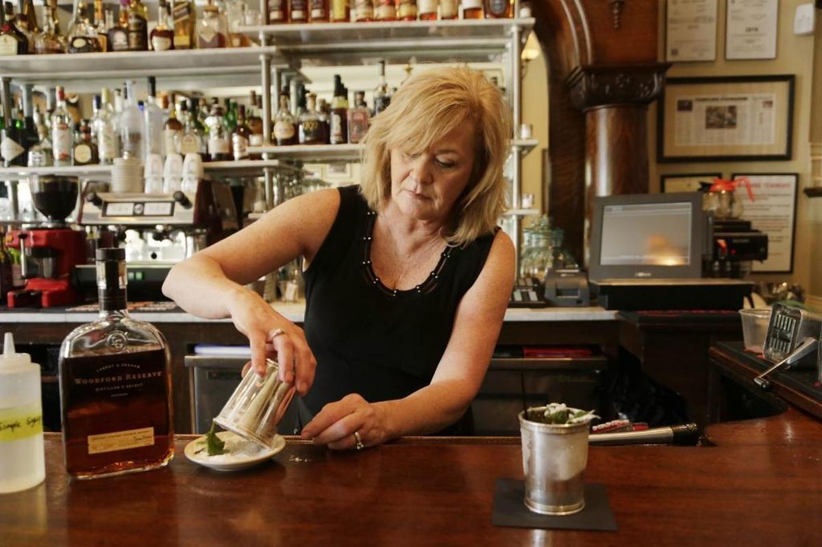 Julie Mora, bartender at Dudley’s on Short Street in Lexington, demonstrated how to make a mint julep in 2016. She starts by coating the rim of the silver julep cup with powdered sugar. Mora prefers using simple syrup made with mint leaves for extra flavor.