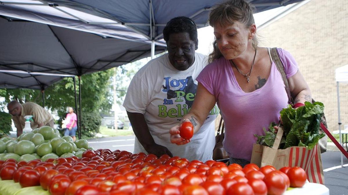 Theresa Hardin, left, and Heather Young selected tomatoes at the Fresh Stop Market in the parking lot at New Beginnings Church on Bryan Avenue.