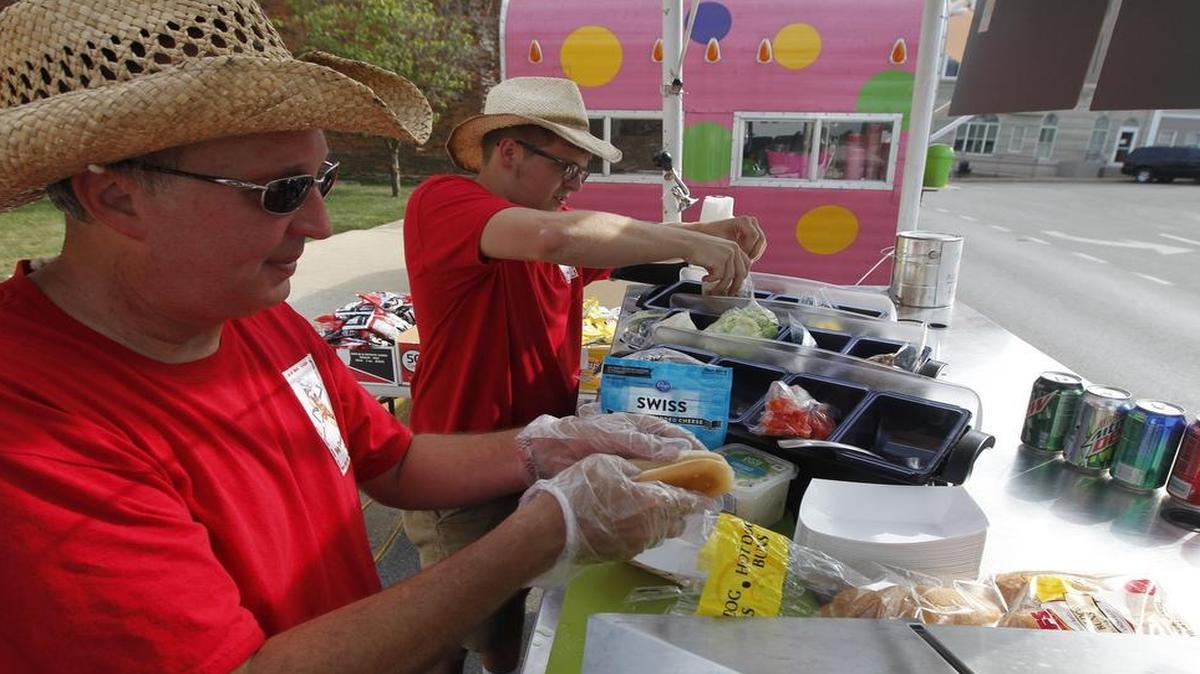 Philip Enlow, left, and Frank Bradford put together a Big Daddy’s hot dog for a customer recently at the Third Thursday concert series in Paris.