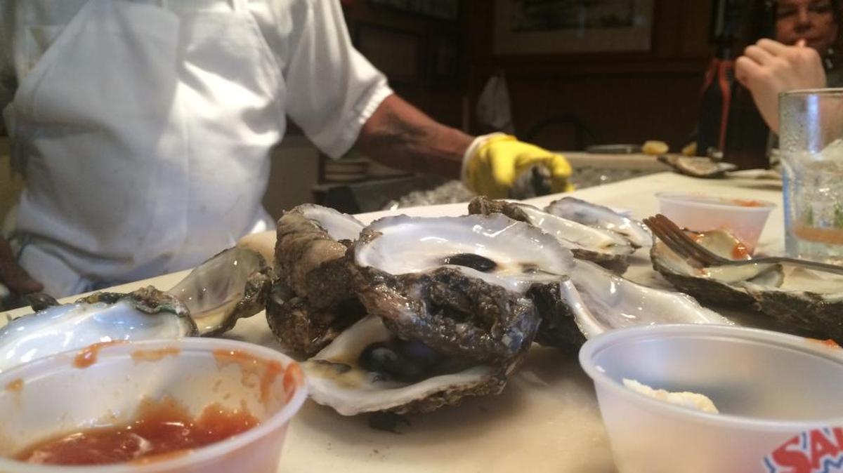 Oyster shells, cocktail sauce and Uptown T the oyster shucker at Pascal’s Manale.