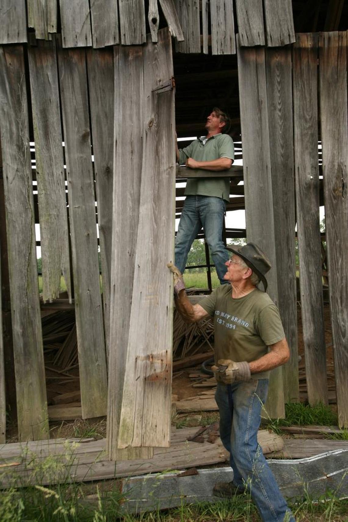 David Odor, bottom, and George Gatewood removed a piece of siding from a barn on a farm in Woodford County in 2007. Gatewood’s company, Longwood Antique Woods, recycles wood from barns and structures and sells it as flooring and other architectural material.