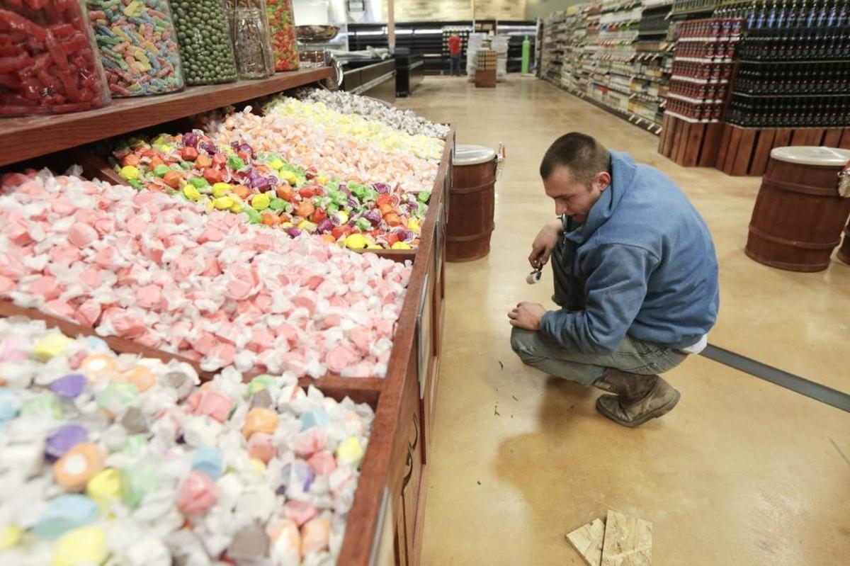 In 2016, Justin Newsome, hired by the store after starting through a temp agency, worked on Lucky's Market display case of bulk candy. The store is closing.