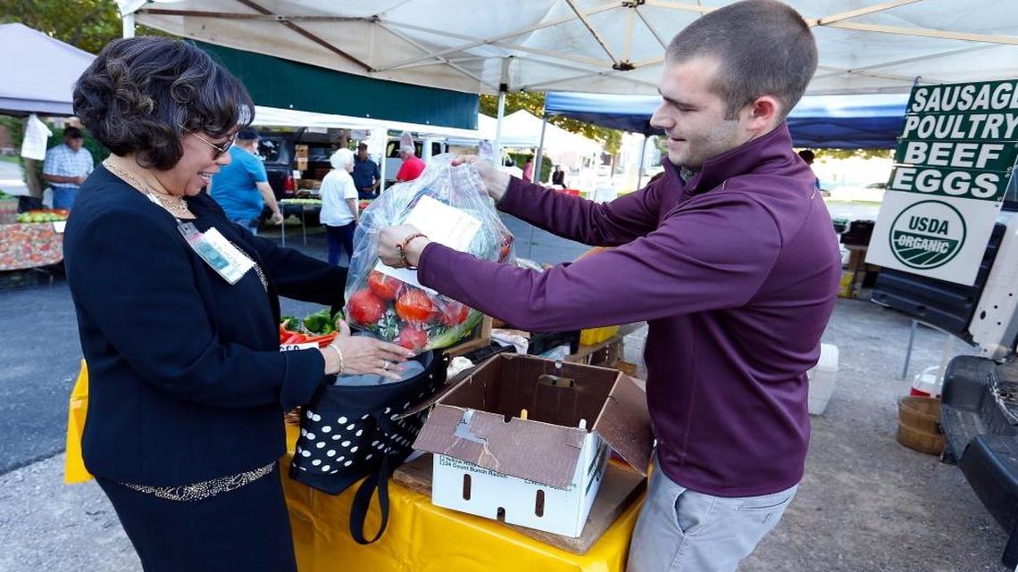 Danita Ross, left, picked up her CSA share from Evan Janes, right, at the Elmwood Stock Farm stand at The Lexington Farmers Market. UK and Community Ventures have partnered in a pilot project, called Bluegrass Harvest, in which employers offer a perk: a $200 voucher for employees to use for a share in a CSA. Ross is a vice president of human resources with Hospice of the Bluegrass, one of the employers participating in the pilot project.