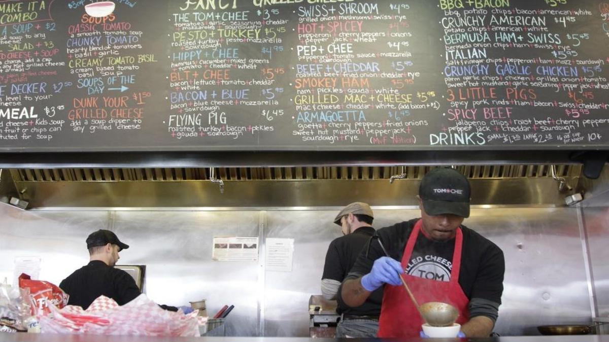In this 2014 file photo, James Lewis served a cup of soup under the extensive menu at Tom + Chee on War Admiral Way in Lexington.