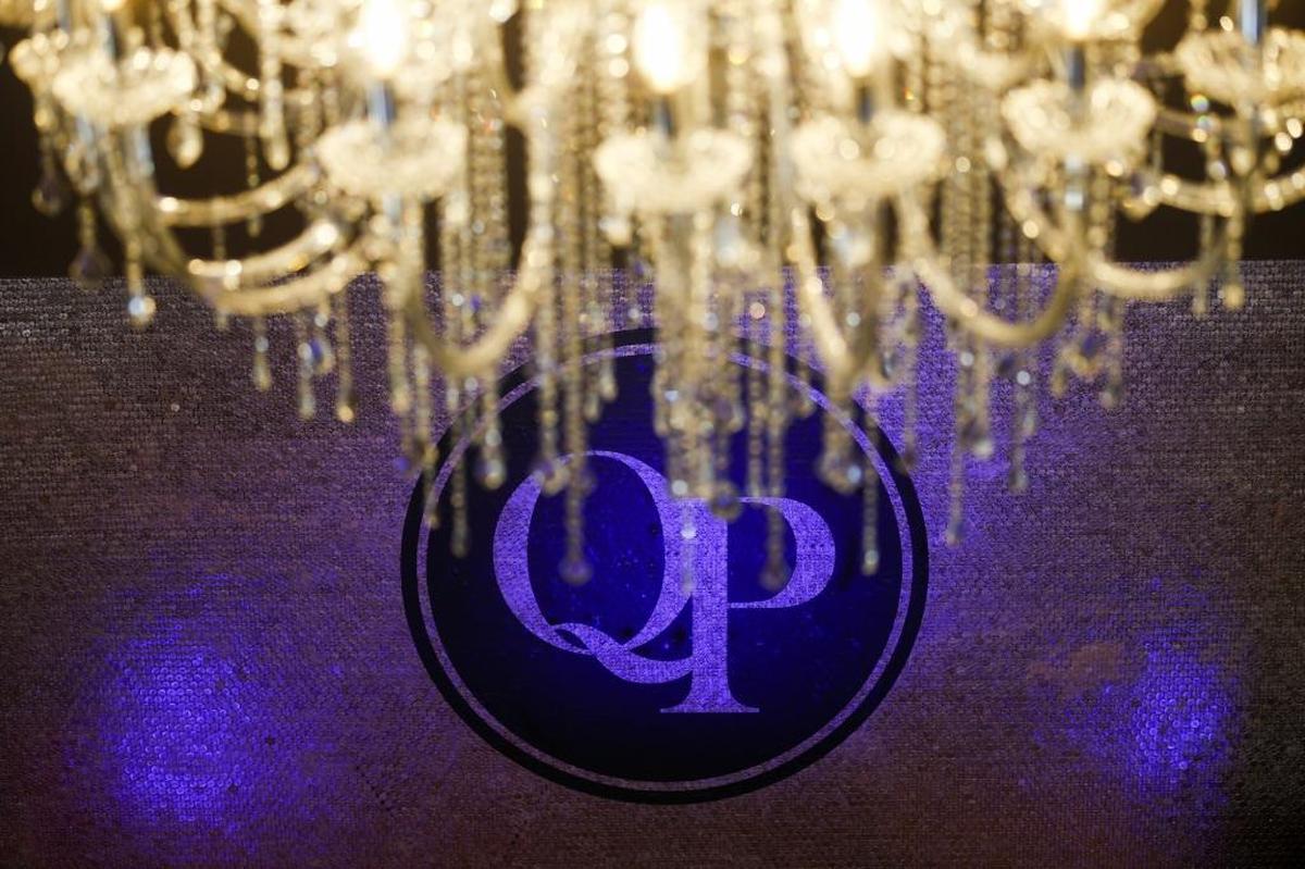 A chandelier hangs above a wall decorated with 150,000 pennies and the logo for QP. The two-story bar will feature cocktails, premium bourbon, ... and movie theater candy.