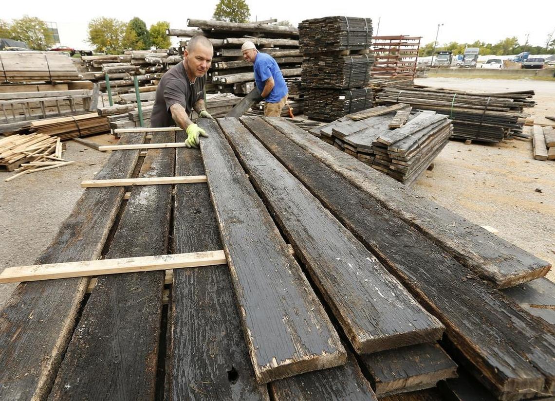 Charlie Harris, left, and David Hopkins, right, stacked planks at Old World Timber. Harris was hired after spending more than two decades in prison. He credits the Browns with helping him by putting trust in his ability to learn new skills.
