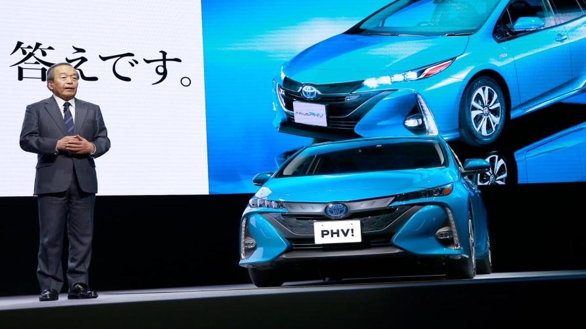 Toyota Motor Corporation's Chairman of the Board of Directors Takeshi Uchiyamada speaks with a Toyota new Prius PHV plug-in hybrid during a press conference rolling out the new Prius PHV in Tokyo, Wednesday.