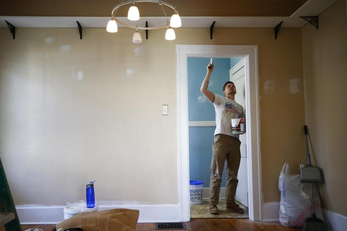 Aaron Withers, of Lexington, worked to paint a door frame in a house in Penmoken Park which will be listed for sale following renovations. Lexington is currently facing a housing shortage which is causing problems for home buyers.