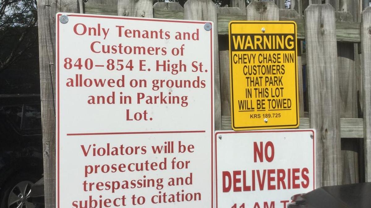Signs behind the Saratoga Center on High Street where customers for Chevy Chase Inn are warned that they will be towed. A security guard periodically asks parkers where they are going.