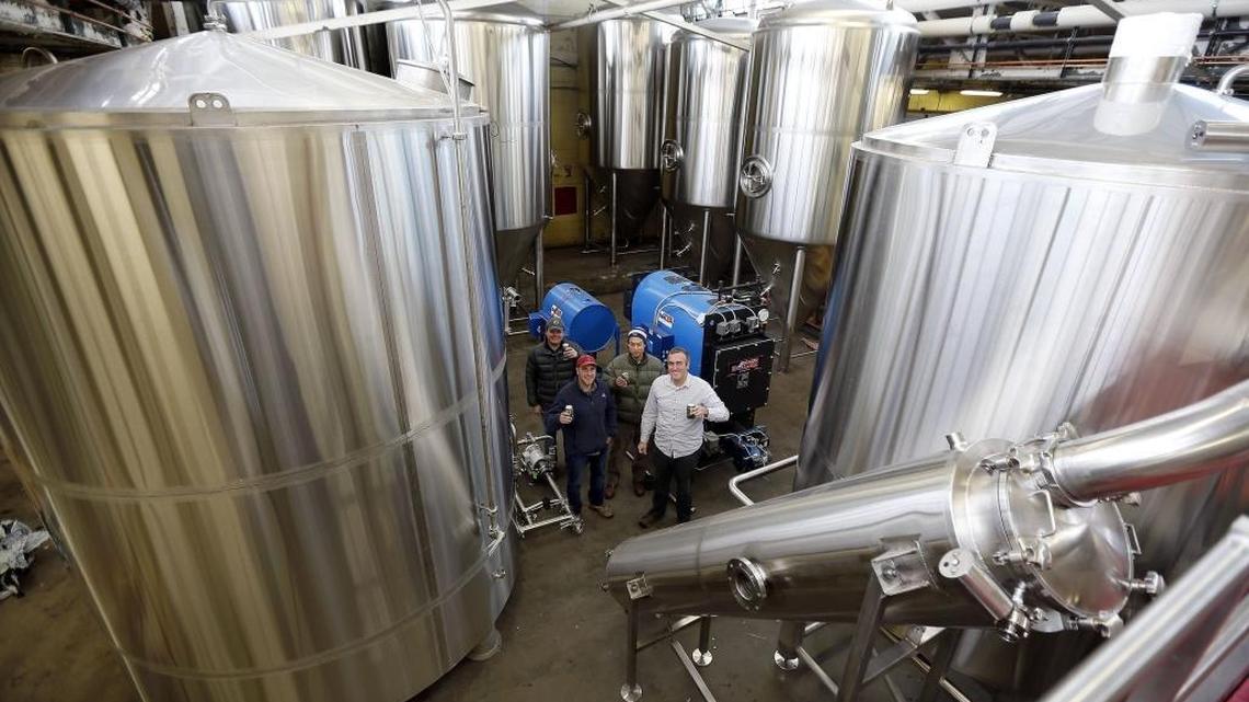 West Sixth Brewery founders, left to right, Brady Barlow, Joe Kuosman, Robin Sither and Ben Self posed by new fermenters and liquor tanks in 2014 during their first big expansion. The founders think their company’s growth during its first five years has been fueled in part by community engagement, philanthropy and generosity to employees.