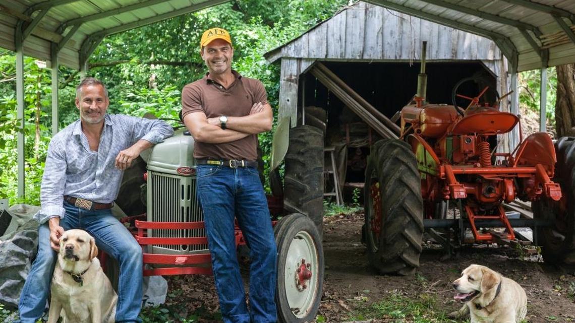 Jon Carloftis sported his AGR fraternity cap alongside his partner Dale Fisher and their English Labradors Gertrude, left, and Lily. The two tractors will be used as sculptural accents among the landscaping at The Summit at Fritz Farm.
