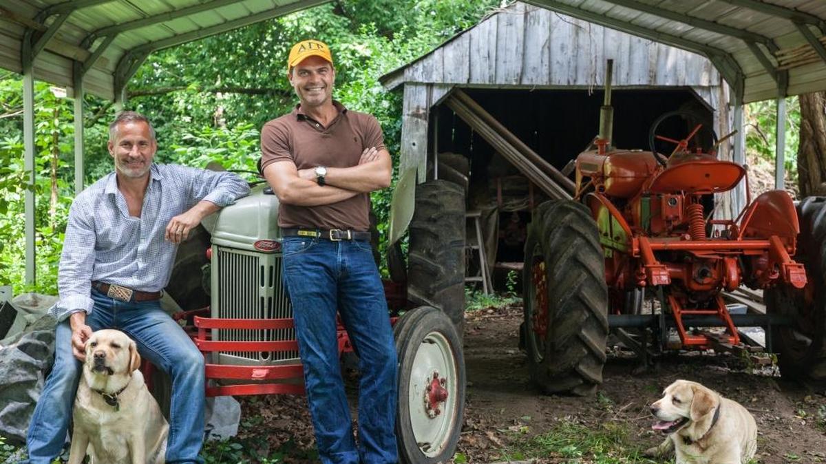 Jon Carloftis sported his AGR fraternity cap alongside his partner Dale Fisher and their English Labradors Gertrude, left, and Lily. The two tractors will be used as sculptural accents among the landscaping at The Summit at Fritz Farm.