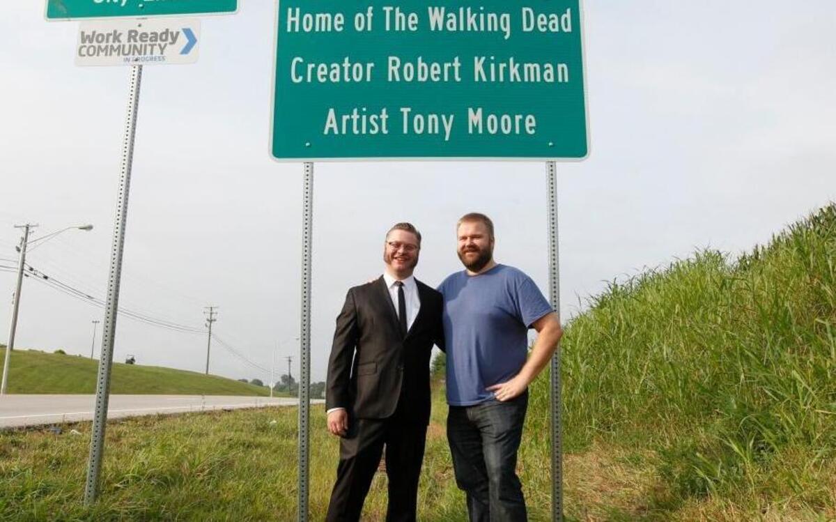 In this 2016 file photo, comic book writer Robert Kirkman (right) and artist Tony Moore stand in front of the city welcome sign that includes their names before the opening of The Walking Dead Day in downtown Cynthiana. Kirkman is now developing shows for Amazon’s streaming service.
