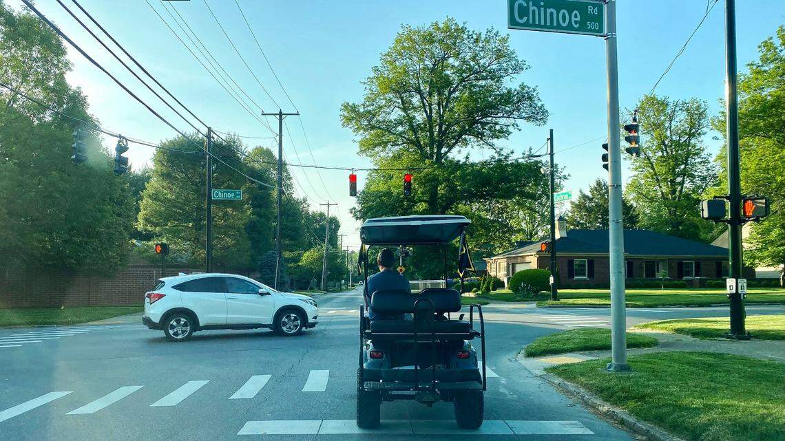 A driver on a golf cart at the intersection of Lexington’s Chinoe and Cochran Roads during the morning commute, May 20, 2021.
