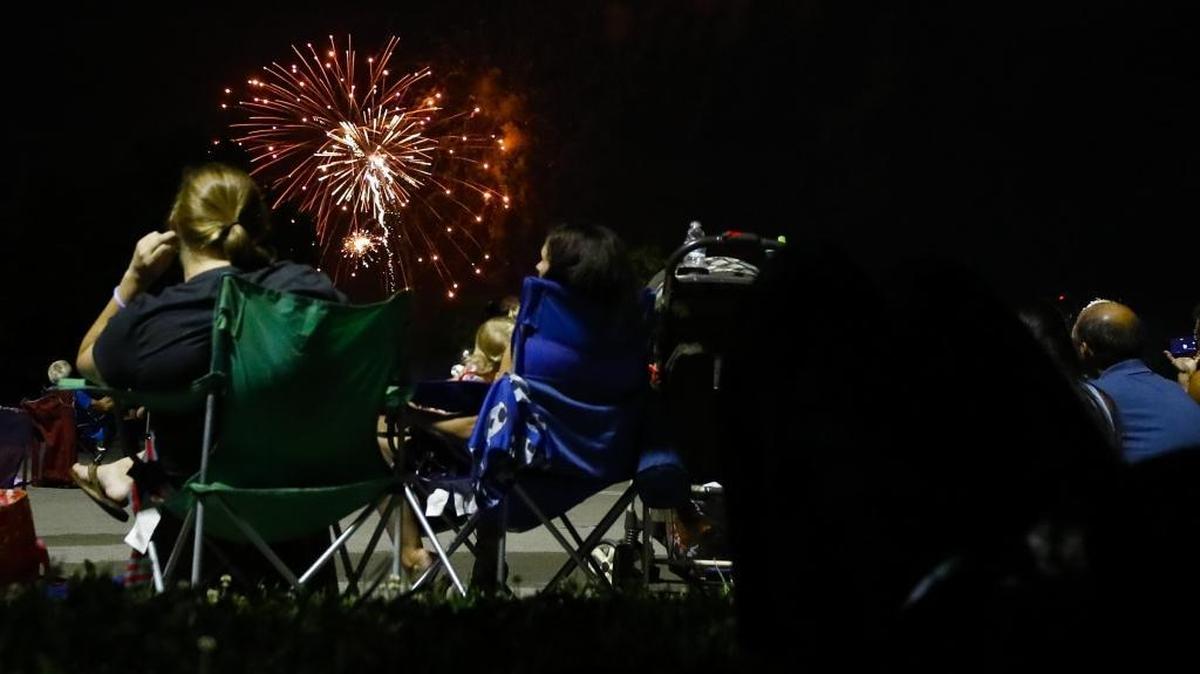 People watch the city Fourth of July fireworks display from a parking lot at Kroger Field.