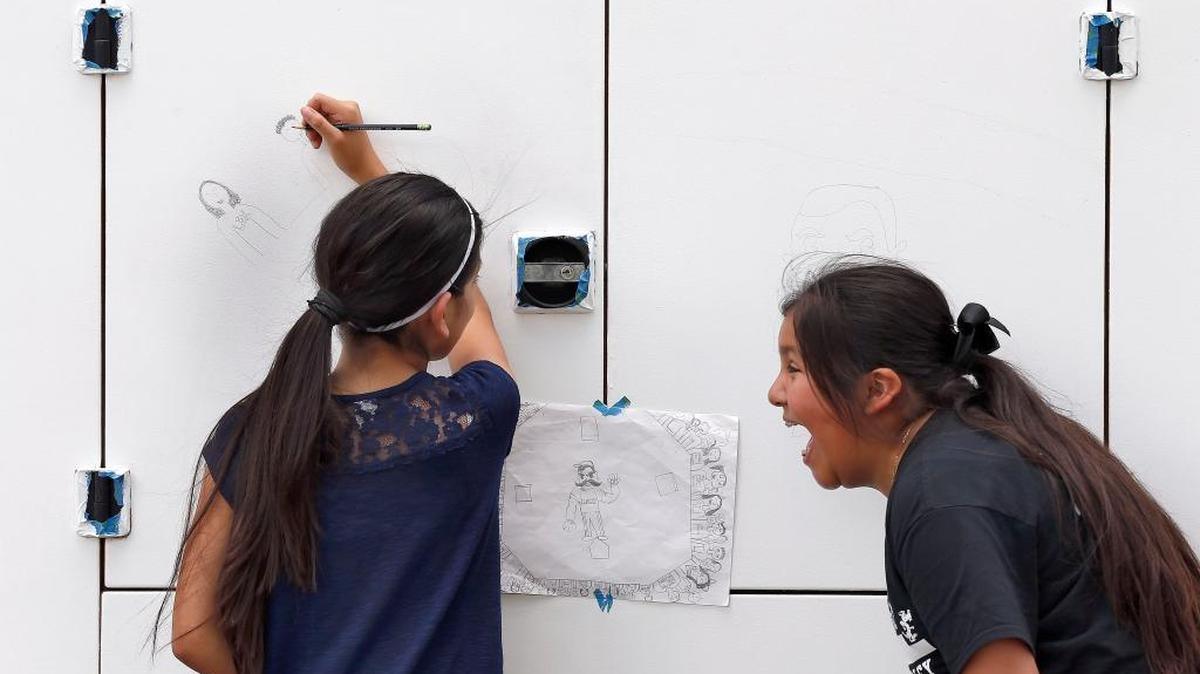 Nayely Ramirez, left, and Paulina De La Roas, both 11-year-old 5th graders, broke into laughter as they sketched the initial part of a mural at Whitaker Bank Ballpark.