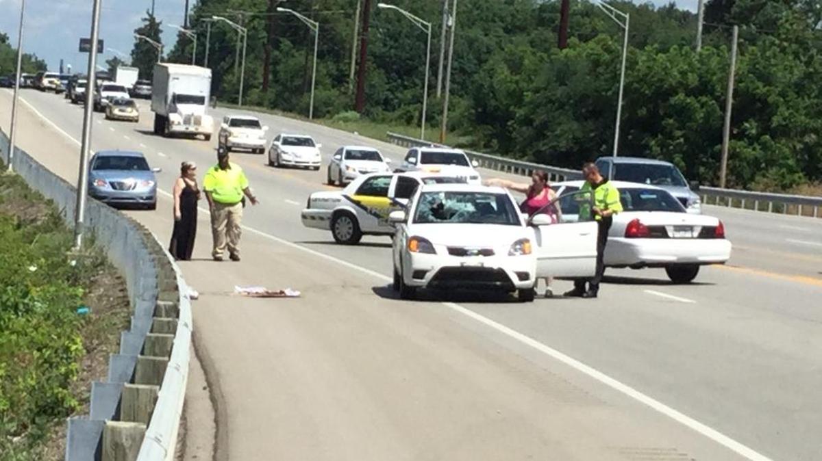 A man attempted to cross Winchester Road Friday afternoon when he was struck by the white car, shown here with the open driver’s side door, police said. The man’s injuries were not believed to be life-threatening. The collision left a hole in the windshield.