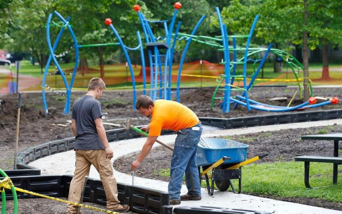 Andrew Keilholz, left, and Nick Lacker, both with Schunk Excavating & Trucking of Cincinnati, installed a plastic border Monday as they built the new playground in Woodland Park.