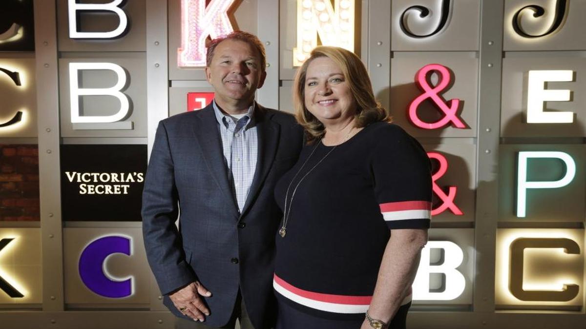 Tim Cambron and Anna Cambron, the president and the CFO of Ruggles Sign Company, a family-owned business in Versailles. Behind them are samples of signs, including many recognizable brands.