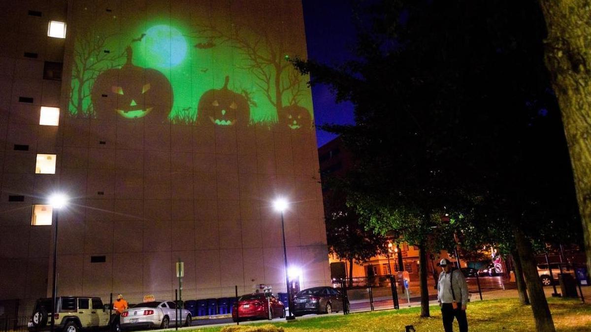 Halloween images were projected onto the east side of the Phoenix building in downtown Lexington this month after the city installed equipment in Phoenix Park. In the foreground, Jason Ervin, 36, who lives in the Park Plaza apartments, let his dog Joey run around in the dog park.
