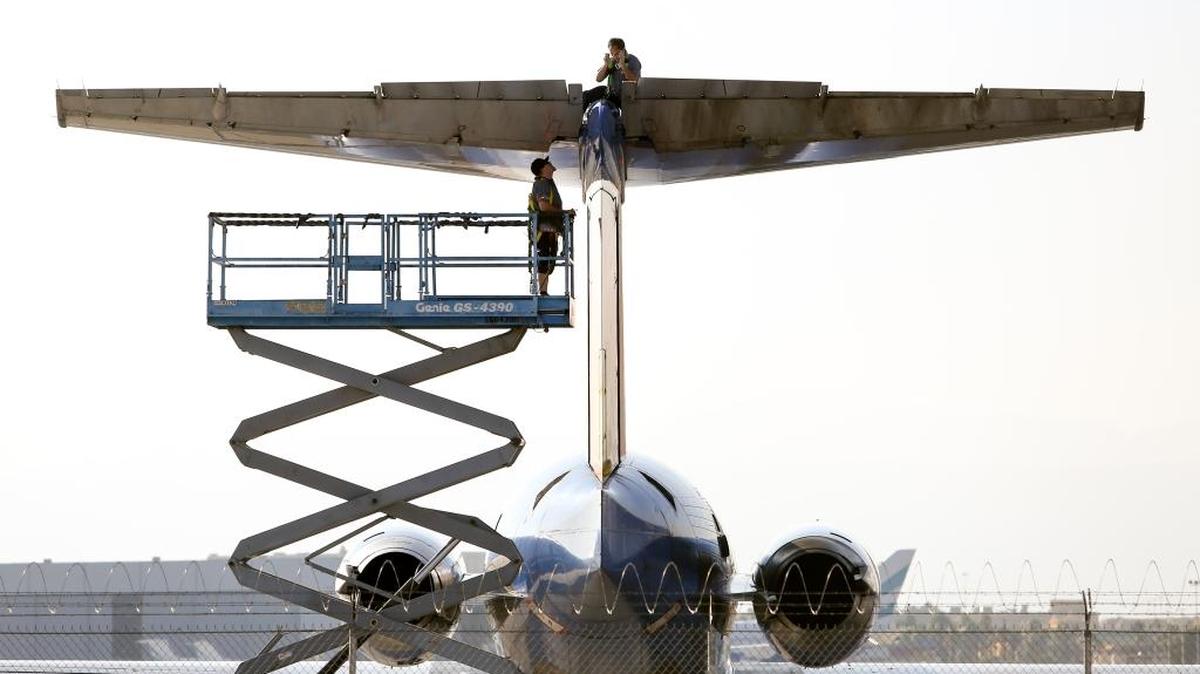Two maintenance crew members worked on on the tail section of an Allegiant Air MD-80 at McCarran International Airport in Las Vegas on Oct. 25. Allegiant executives say they are phasing out the aging MD-80 model in coming years.