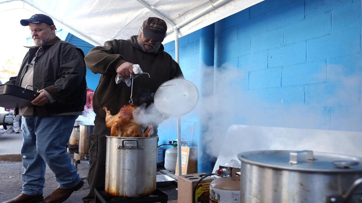 Dean Newby carefully lifted a deep-fried turkey from the hot oil as Jeff Couch readied a pan for the bird outside Double H BBQ on Versailles Road.