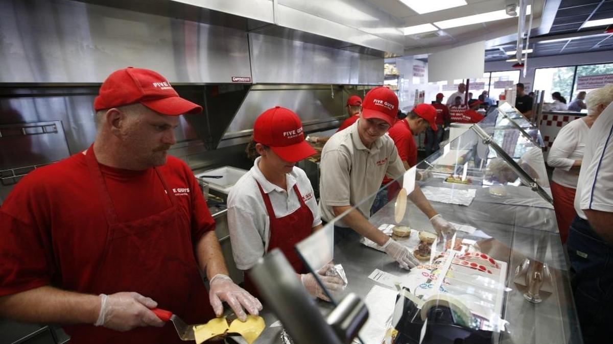 Rob Badd, left added meat to burgers on the line at Five Guys in Lexington, Ky., Friday, July 10, 2009.