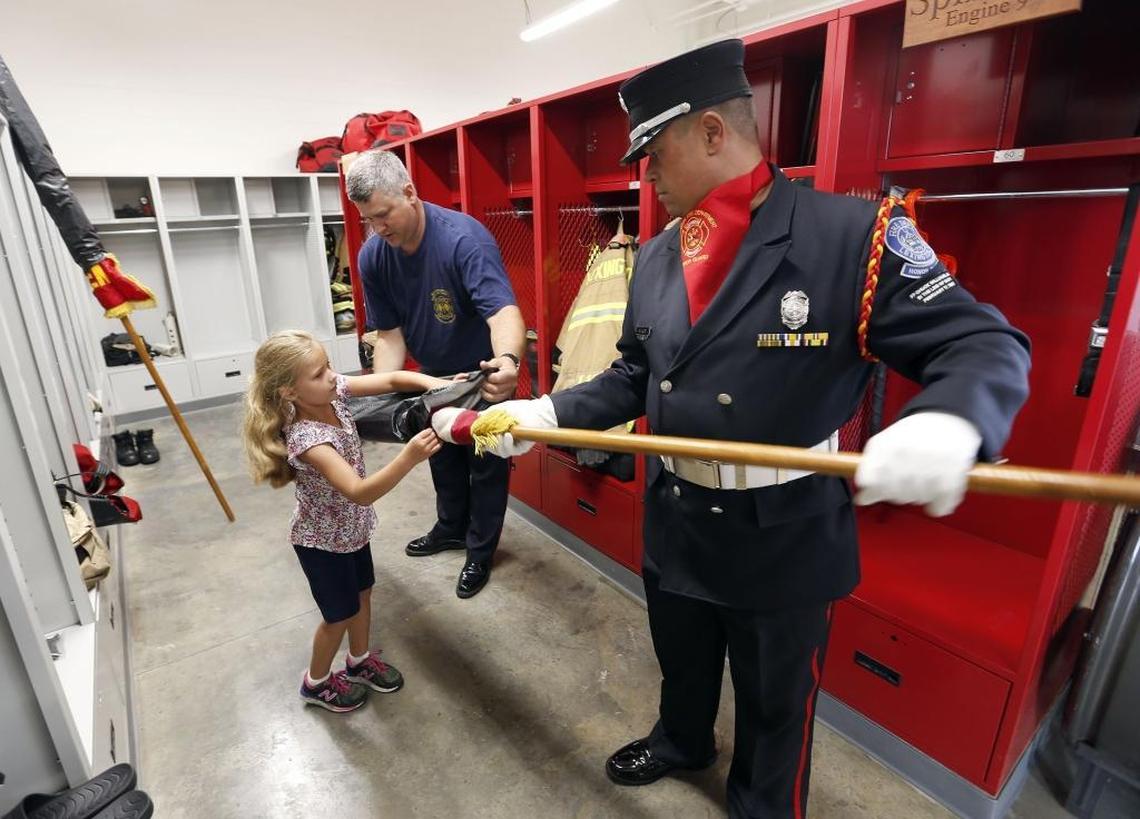 Lilly Bramlage, 6, helped her dad, Maj. Marc Bramlage, middle, and firefighter Mike Hurt put away a U.S. flag after Thursday’s ceremony to dedicate new Station 2. It replaces the old Station 2, at 415 New Circle Road. That building, built in 1954, once housed the county fire and police station, including jail cells, before the merger of local government in 1973. The new station, with 14,000 square feet, will relieve overcrowding at the old one. Station 2 is home to engine 2, ladder 5 and emergency care 2, and to a district major who oversees several firehouses.
