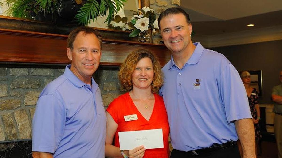 Kristin Ingwell Goode of God’s Pantry received a grant from Doug Flynn, left, and Coach Matthew Mitchell, right, co-hosts of the Children’s Charity Classic June 24-25 in Lexington. God’s Pantry is one of the 38 charitable organizations that received grants at the Children’s Charity Classic’s tee-off reception.