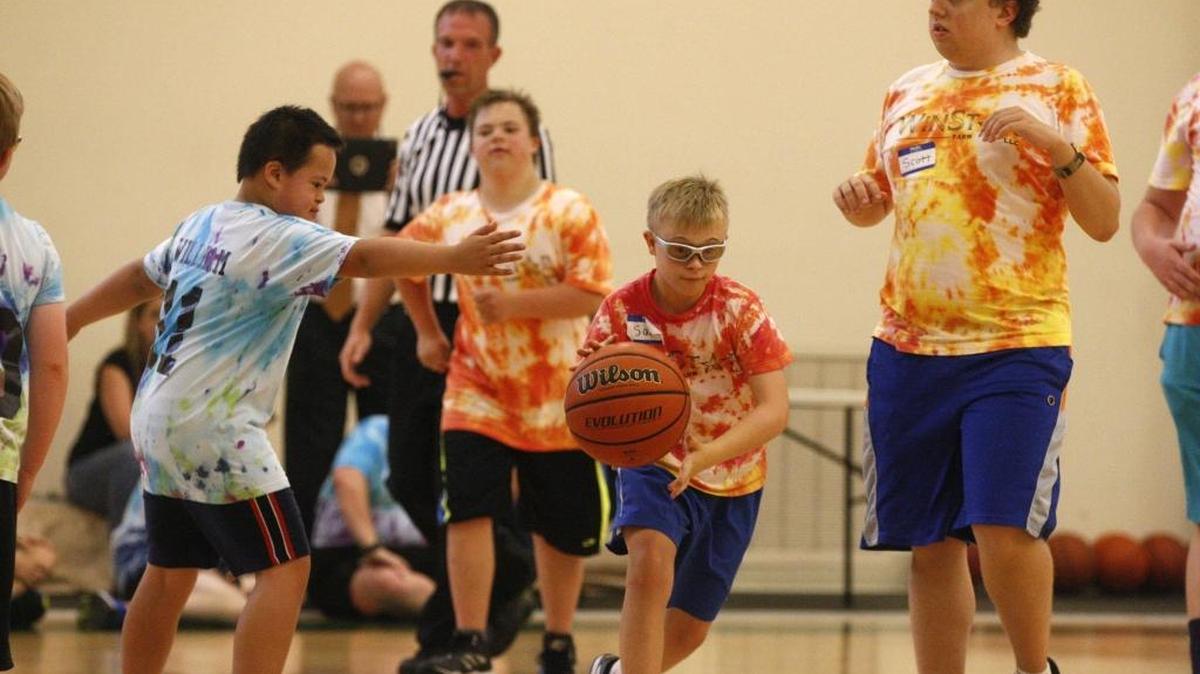 Red Fire Tiger Sam Elbert drives the ball into Blue Dribbling Dolphin's side of the court avoiding a block from Blue Dribbling Dolphin William Rinker during the final game of a basketball camp for people with special needs on July 22, 2016 at WinStar Farms in Versailles, Ky.