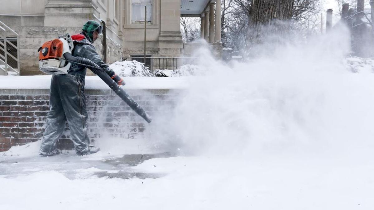 Lamont Gray used a gas-powered backpack blower to remove the fresh snow off the sidewalk around The Carnegie Center for Literacy and Learning, on February 10, 2014.