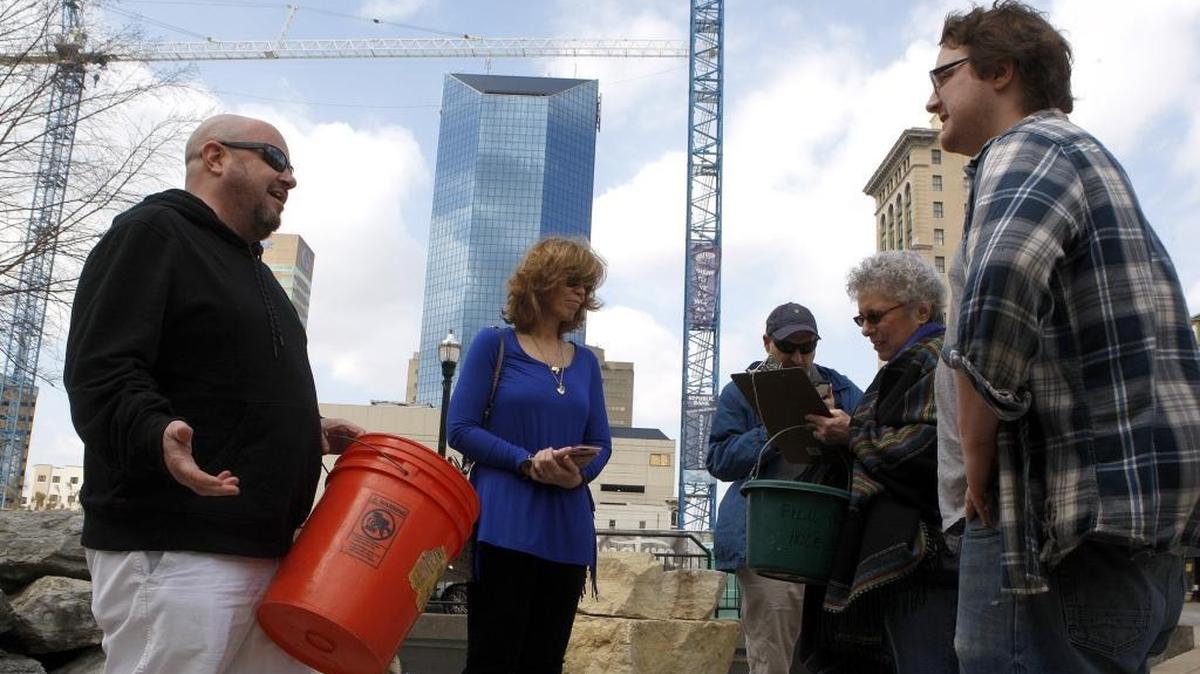 Dan McBrayer, left, held an empty bucket as he chanted with other participants as they gathered for a “Fill in the Hole” rally near CentrePointe.