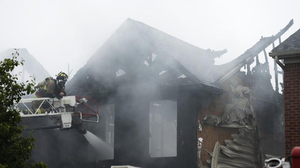 Lexington firefighter Anthony Porco hosed a smoldering fire from a ladder on Stansberry Cove in Lexington on May 17.