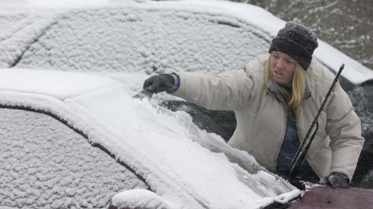 Sarah Hayden scrapes the snow and ice off her windshield on Delzan Place during an afternoon snow storm in Lexington, KY, Thursday, January 16, 2003.