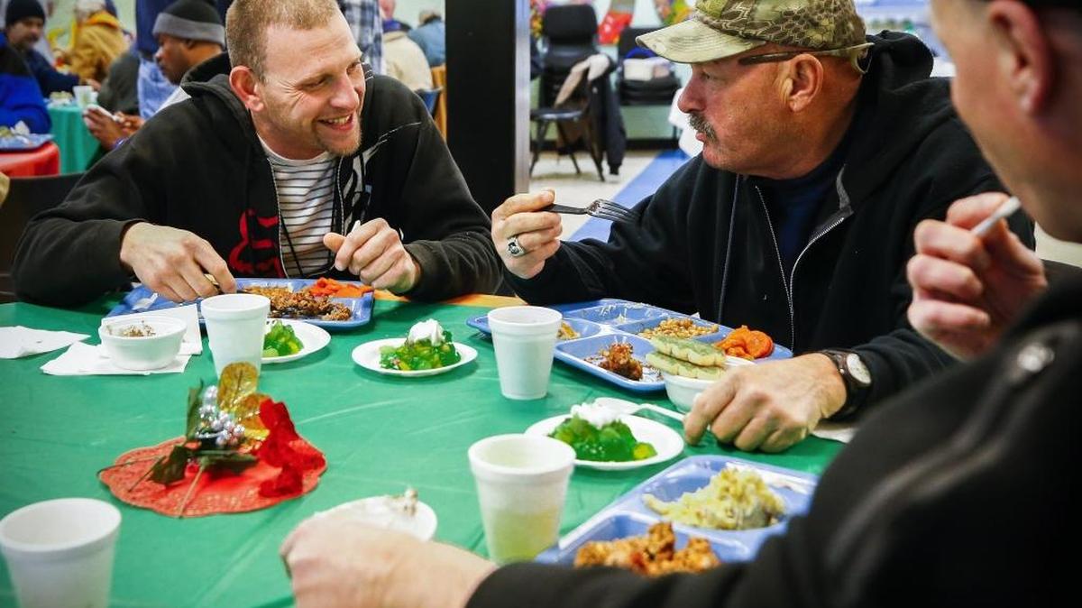 Joseph Ferguson joked with Marty Hall at the Jacobs Hope Cafeteria in Lexington Wednesday night. Ferguson is part of the Hope Center Recovery Program for Men and Hall has been part of the center’s veterans program. The free meal is part of the Jacobs Hope Cafeteria’s 12 Days of Christmas and was prepared by volunteers who have completed Hope Center recovery programs. The Jacobs Hope Cafeteria, which is part of the Hope Center, serves three hot meals a day to people currently part of Hope Center recovery programs, emergency shelter and residents of the The Don and Cathy Jacobs House as well as the community.