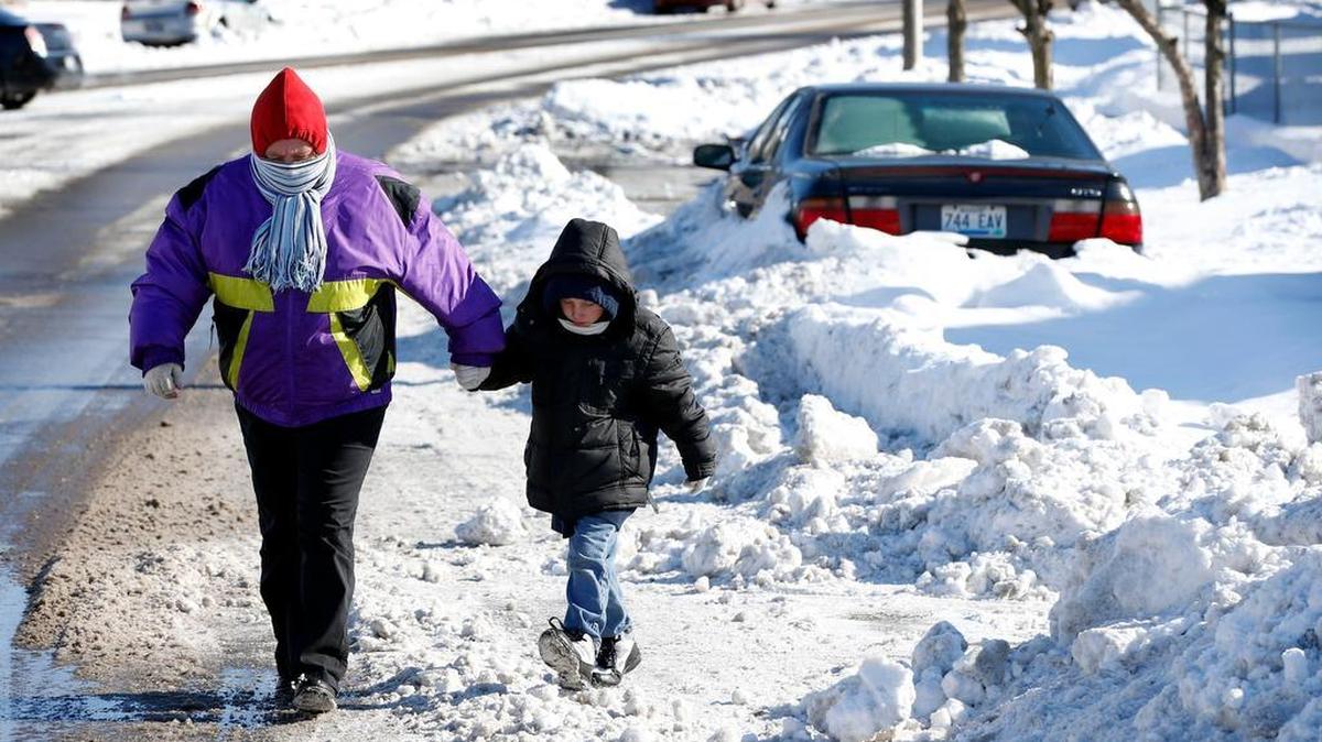 Since the sidewalks were covered with snow, Erie Douglas walked in the street with her 6-year-old grandson Christopher Hough on Elm Tree Lane in Lexington on Feb. 20, 2015.