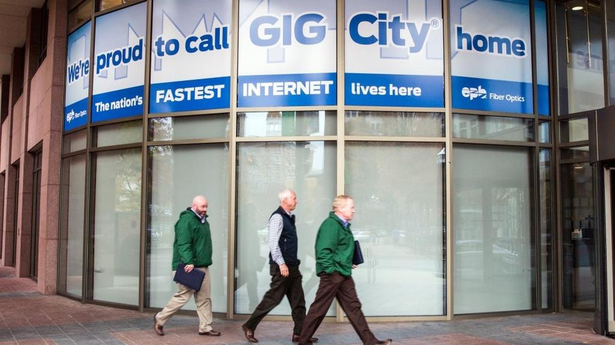 In this Nov. 17, 2014, photo, men walk by a sign in Chattanooga, Tenn., promoting it as Gig City. The city's municipal fiber optic network provides Internet speeds at more than 50 times the national average. Lexington and other cities are trying to duplicate Chattanooga’s efforts.