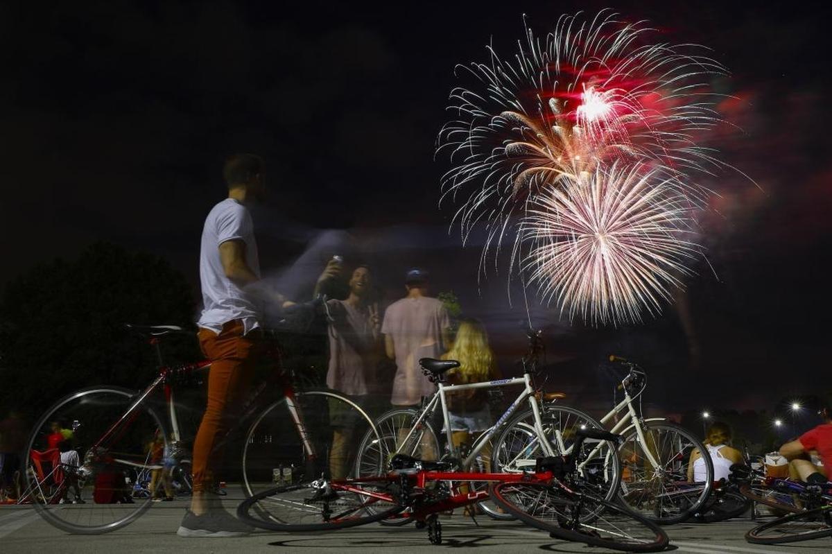 Bicyclists watched the city’s Fourth of July fireworks display from a parking lot at Kroger Field in 2017. This year, the fireworks display will move back downtown.