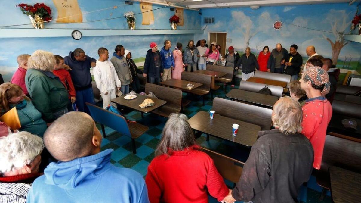 Catholic Action Center co-director Ginny Ramsey had the diners hold hands for prayer and the singing of Amazing Grace Thursday during the last lunch at the Catholic Action Center day shelter, 400 E. Fifth St. in Lexington.