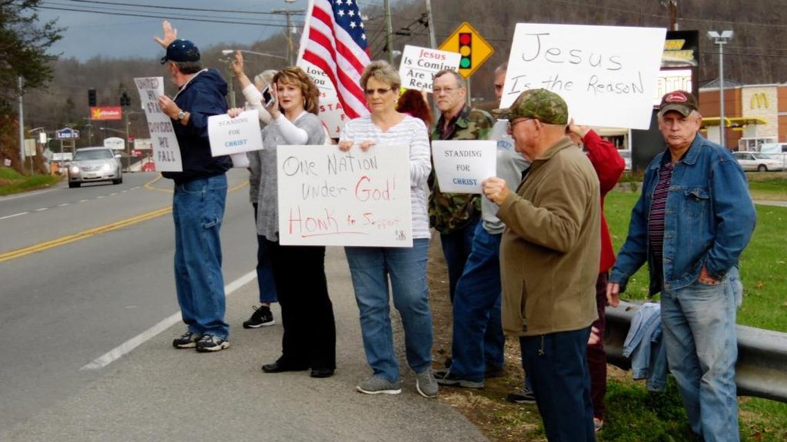 Protesters carrying signs and waving banners stood outside the Johnson County Board of Education office Monday to oppose removal of religious references from school plays and other programs.