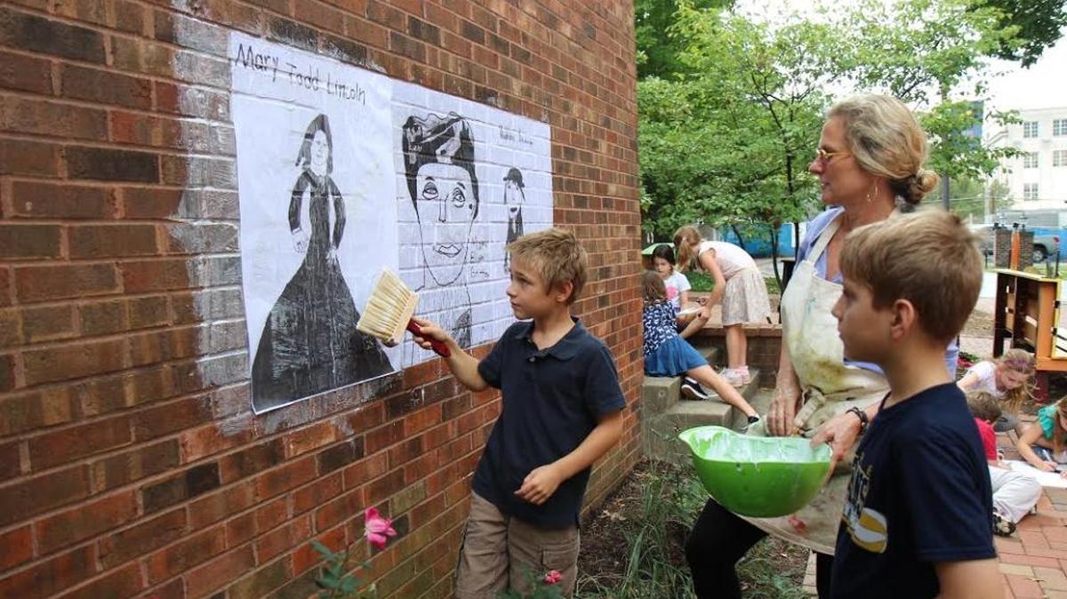 Sayre Lower School art teacher Georgia Henkel, center, and third-graders Dougie Christopher, left, and Brogann Thomas wheat-pasted Lexington’s first public mural celebrating Lexington women of historical significance on the side of a building.