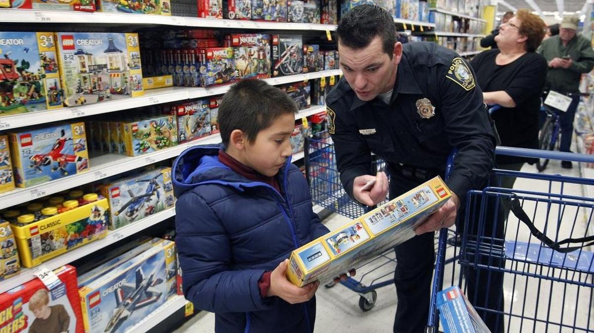 Lexington police Officer B. J. Blank helped Manuel Bissonnette select a toy during Shop with a Hero at Meijer on Saturday.