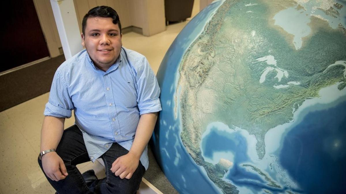 EKU senior Omar Salinas Chacon, who is originally from El Salvador, sits next to an oversized world globe in the Roark Building on EKU’s campus, Thursday afternoon, February 22, 2018.