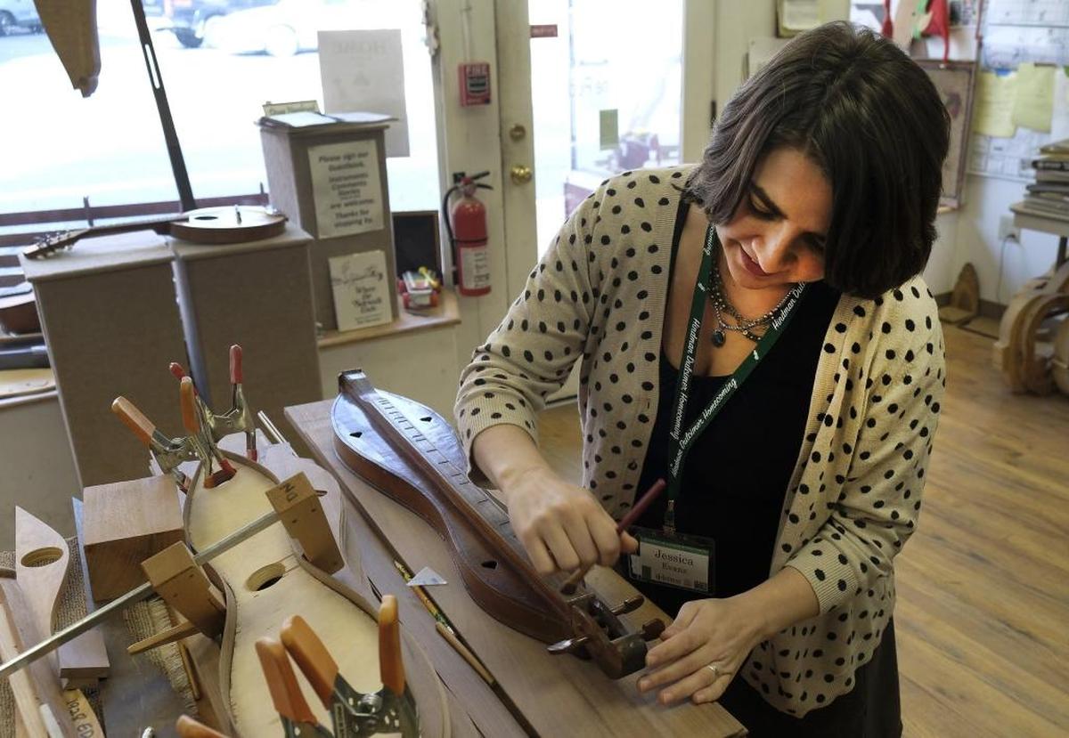 Jessica Evans, program director at the Appalachian Artisan Center, brushes dust from a 1935 Jethro Amburgey dulcimer that a woman in Missouri recently donated to the center’s collection. Amburgey was a pioneering dulcimer maker in Knott County whose work helped inspire the Hindman School of Luthiery, which trains people to make stringed instruments.