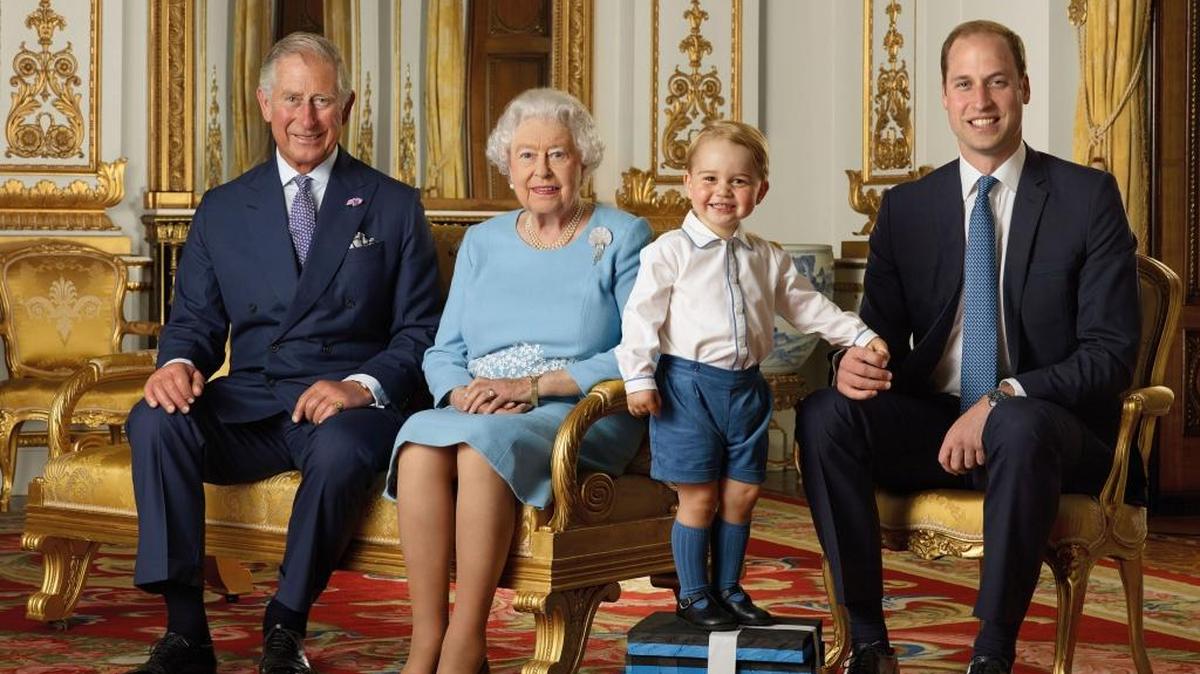 In this image released by the Royal Mail on Wednesday April 20, 2016, Britain's Prince George stood on foam blocks during a photo shoot for the Royal Mail in the summer of 2015 in the White Drawing Room at Buckingham Palace in London for a stamp sheet to mark the 90th birthday of Britain's Queen Elizabeth II. The image features four generations of the Royal family, from left, Prince Charles, Queen Elizabeth II, Prince George and Prince William, the Duke of Cambridge.