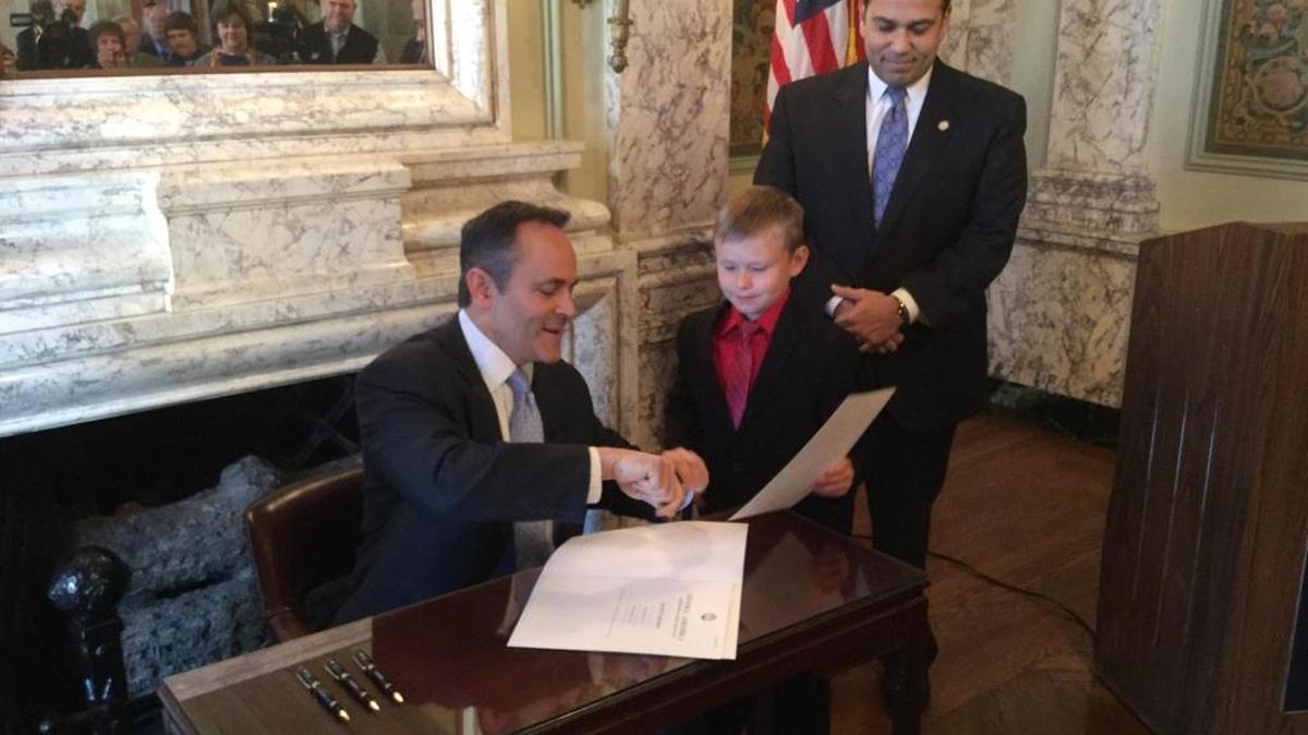 Gov. Matt Bevin presents the pen he used to sign Senate Bill 193 into law to Noah Greenhill of Pikeville as Sen. Ralph Alvarado, R-Winchester, watches in the state Capitol on April 12, 2016.