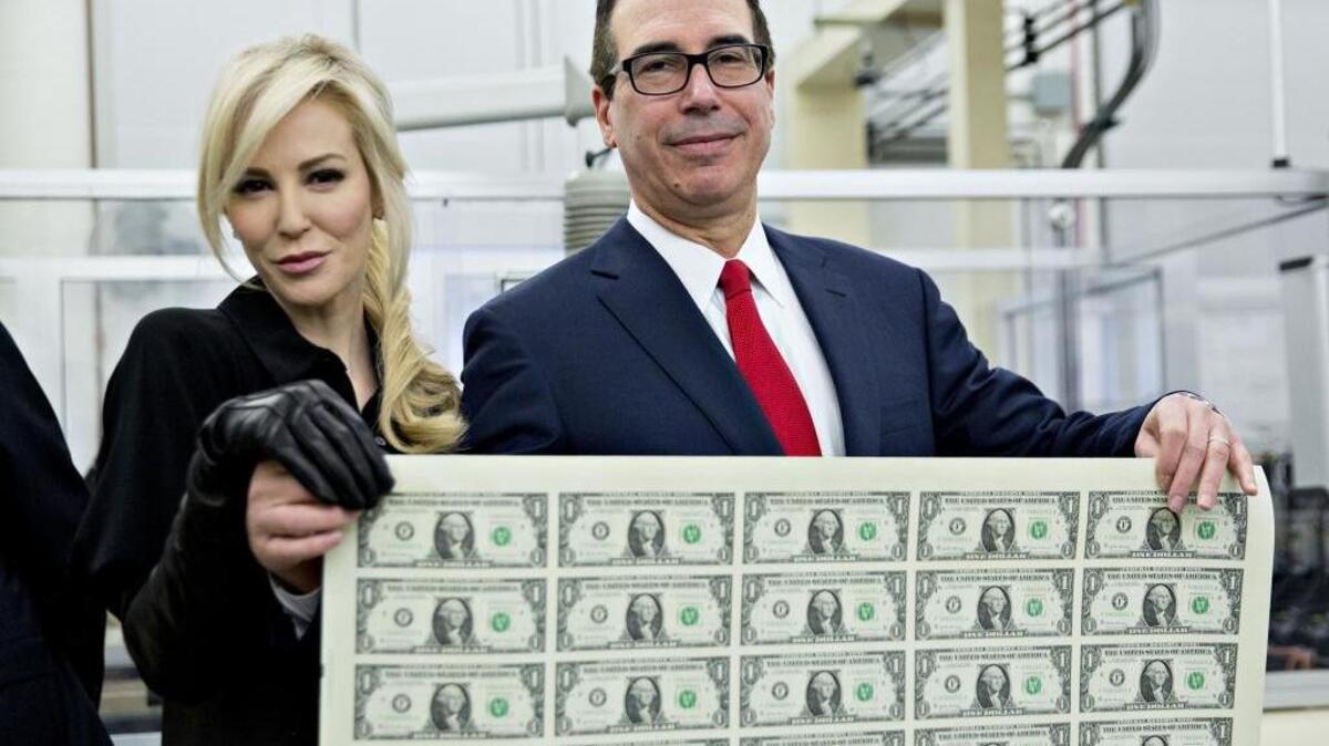 Treasury Secretary Steven Mnuchin, right, and wife, Louise Linton, hold an uncut sheet of $1 dollar notes. The new $1 bills, with Mnuchin and U.S. Treasurer Jovita Carranza's signatures, are expected to go into circulation in December.